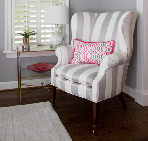 A bold gray and white armchair with a hot pink and white pillow. Look decorated by Diane Litz.